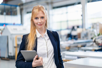 Portrait of confident businesswoman with tablet in factory