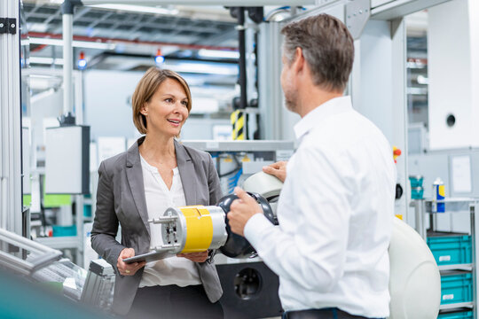 Businesswoman and man talking at assembly robot in a factory