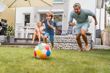 Father and son playing football in garden