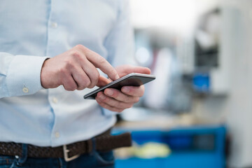 Close-up of businessman using cell phone in a factory