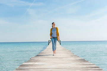 Happy woman walking on jetty, Mallorca, Spain