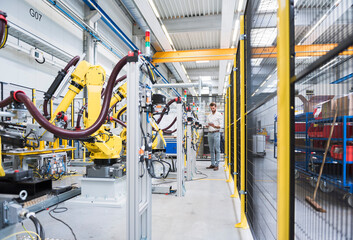 Full length of confident engineer working at automated robotic factory