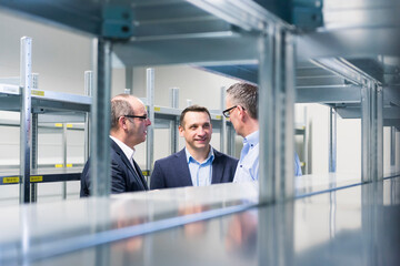 Three businessmen having a discussion in a factory storehouse