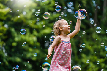 Cheerful girl amidst bubbles at park