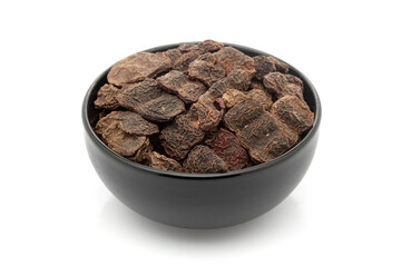 Close-up of Dry Organic Shikakai (Acacia concinna) fruits, in black ceramic bowl. Isolated on a white background.