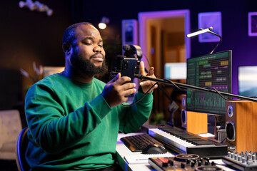 African american songwriter singing his new creation in home studio, recording audio files of his...