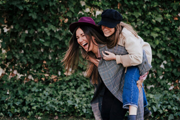 Laughing woman giving her friend a piggyback ride