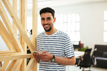 Portrait of smiling young man with cell phone in office
