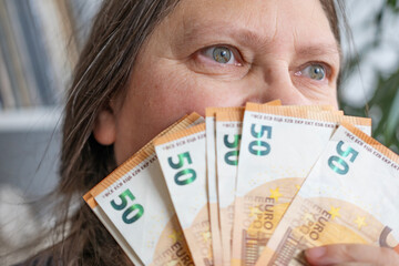 woman holding euros, euro money in fan, rejoices in success, anticipates what to spend it on,...