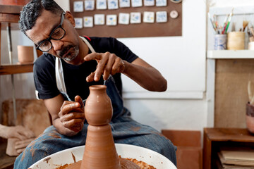 Close-up of male potter making earthenware while sitting in workshop