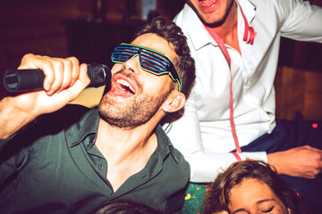 Close-up of young man singing karaoke while enjoying with friends in party