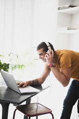 Smiling young man wearing headphones and using laptop