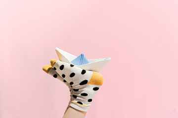 Paper boat on the feet of a girl wearing dotted socks