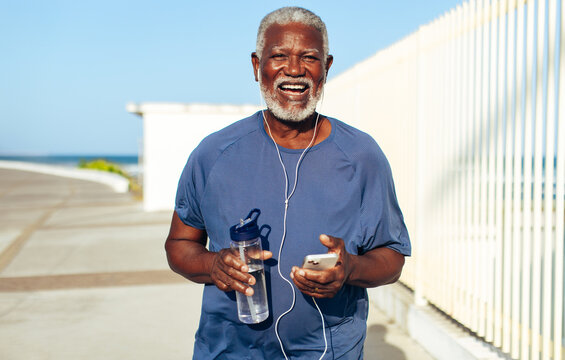 Elderly African American man enjoying music during a sunny walk