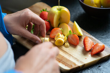 Woman chopping fruits in her kitchen, close up