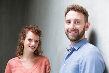 Portrait of smiling man and woman at concrete wall