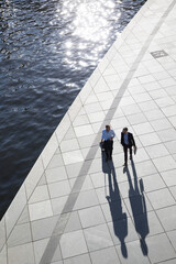 Two businessmen walking and talking at the riverbank