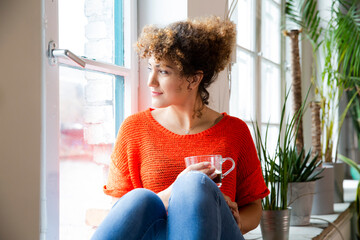 Woman with a coffee looking out of window in office