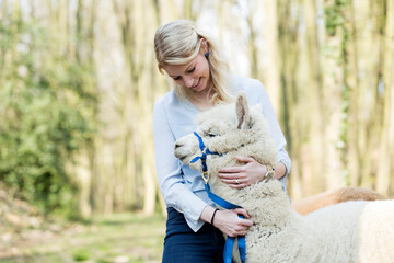 Happy woman cuddling alpaca