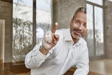 Smiling businessman pointing on glass pane