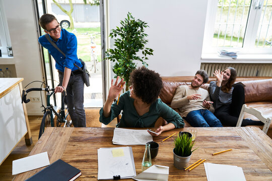 Coworkers waving at young man with bicycle arriving in modern office