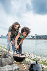 Germany, Cologne, couple having a barbecue at the riverside