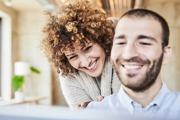 Happy man and woman sharing tablet in modern office