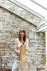 Screaming woman chopping wood in front of a house