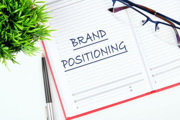Brand positioning is shown written in an open business notebook on a blank sheet
