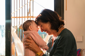 Grandmother holding baby girl, head on head and smiling