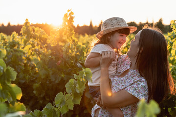 Mother and little daughter in a vineyard at sunset in Provence, France