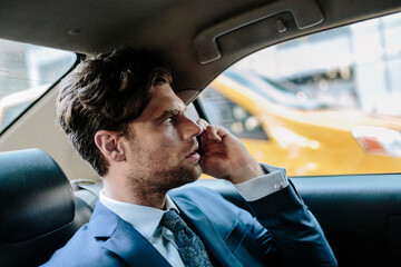 Businessman sitting in taxi, using smart phone