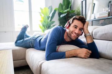 Relaxed man lying on couch listening to music