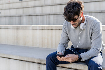 Man sitting on outdoor stairs using smartphone