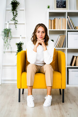 Smiling businesswoman sitting with head in hands on sofa at office