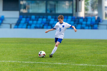 Obraz premium oung soccer player shooting a ball on a modern football stadium. Perfect for sports, youth, fitness, and athletic content. Ideal for promoting energetic and active lifestyles