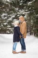 Happy young couple standing face to face in snow-covered winter landscape