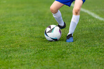 Young soccer player's kick ball. Ball and legs in sharp focus on a lush green field close-up