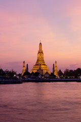 Naklejka premium Wat Arun temple alongside Chao Phraya River during sunset in Bangkok Thailand. 