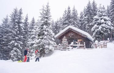 Austria, Altenmarkt-Zauchensee, family with sledges at wooden house at Christmas time