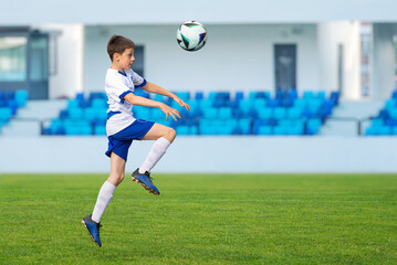 Young soccer player leaps into the air, using his head to direct the ball in a dynamic and intense...
