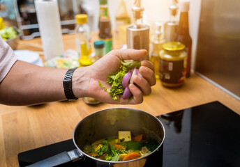 Chef at the kitchen preparing green curry with herbs and rice