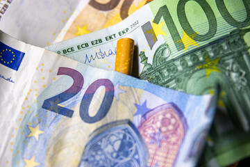 A cigarette is on top of a twenty euro bill