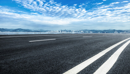 Fototapeta premium Asphalt road and mountains with city skyline background