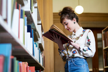 Female student reading book in a public library