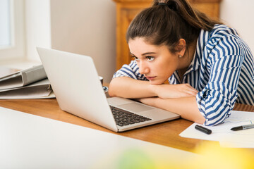 Young woman looking at laptop on desk at home