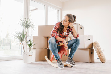 Mature woman moving house, sitting on rocking horse