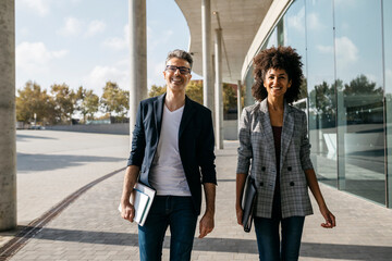 Portrait of two happy colleagues outside office building