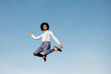 Smiling man jumping in the air against blue sky