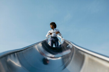 Man climbing on slide looking at distance